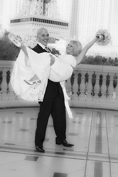 Groom carrying bride in front of Paris Las Vegas during destination wedding