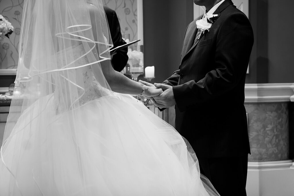 Bride and groom holding hands during wedding ceremony in Napa Valley in black and white