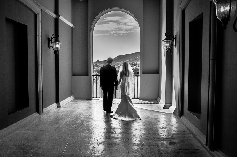 Bride and groom walking through grand estate doorway in black and white
