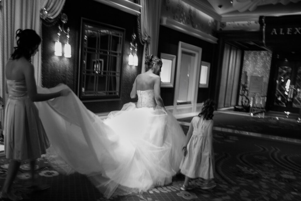Las Vegas wedding bride walking through luxury hotel hallway with flowing gown and flower girl in black and white