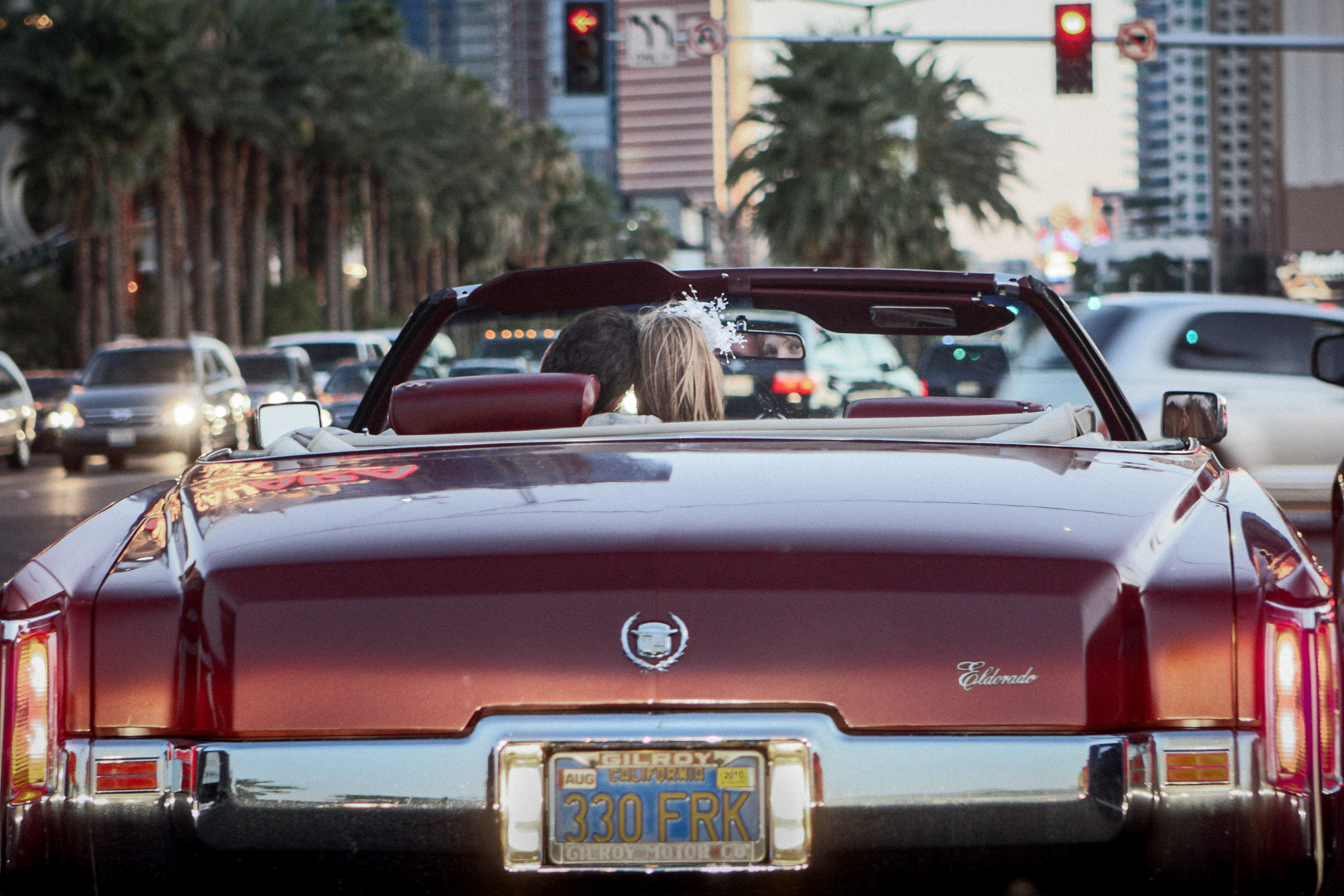 Las Vegas elopement photographer capturing couple in convertible driving down the Las Vegas Strip at sunset