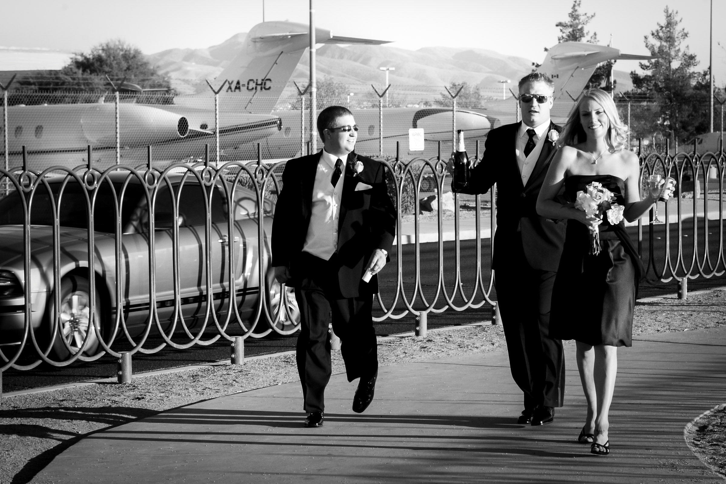 Las Vegas wedding photographer capturing wedding party walking near Las Vegas sign with planes in background