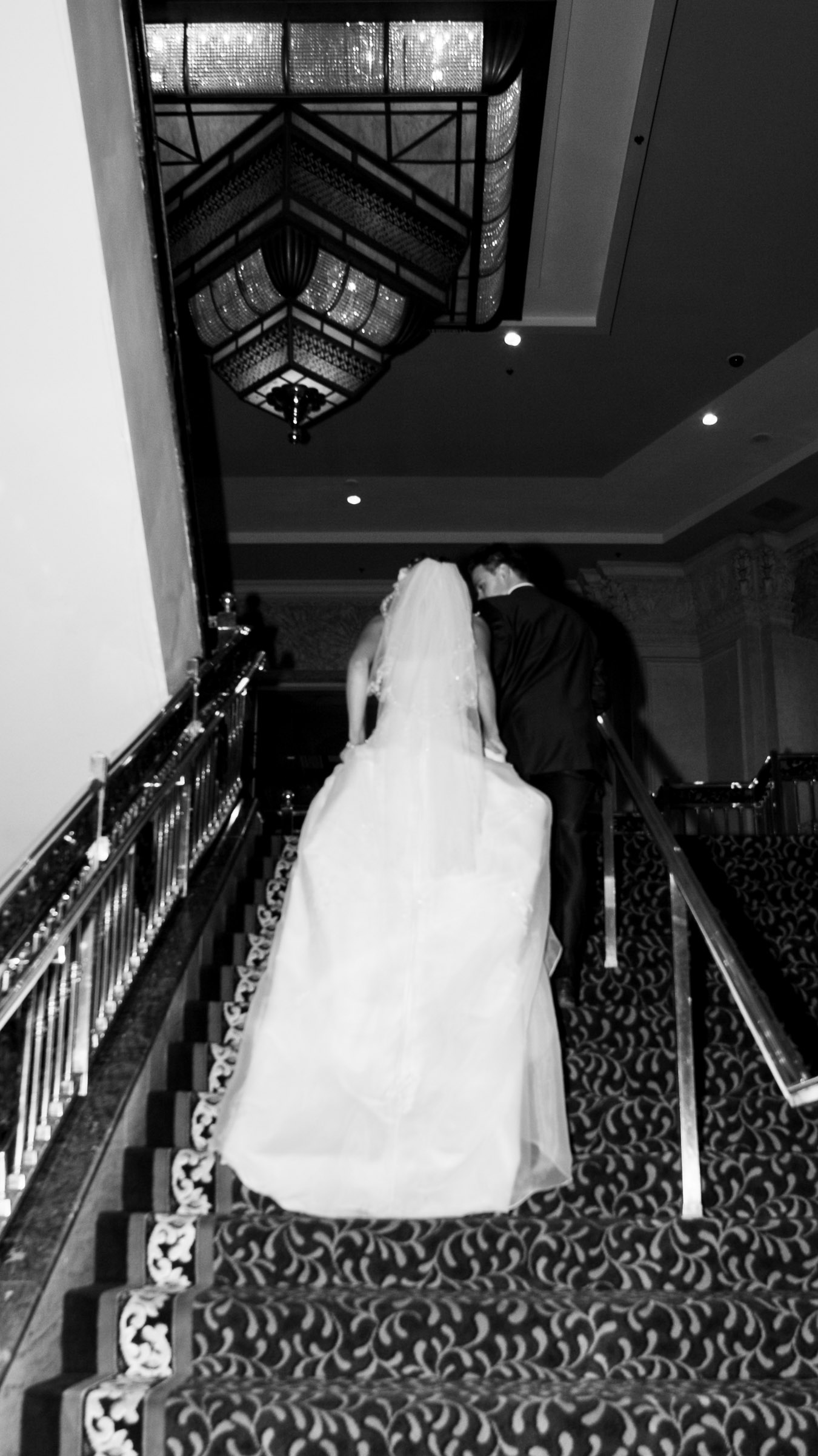 Bride and groom walking up grand staircase at Bellagio Las Vegas captured in cinematic editorial wedding photography style