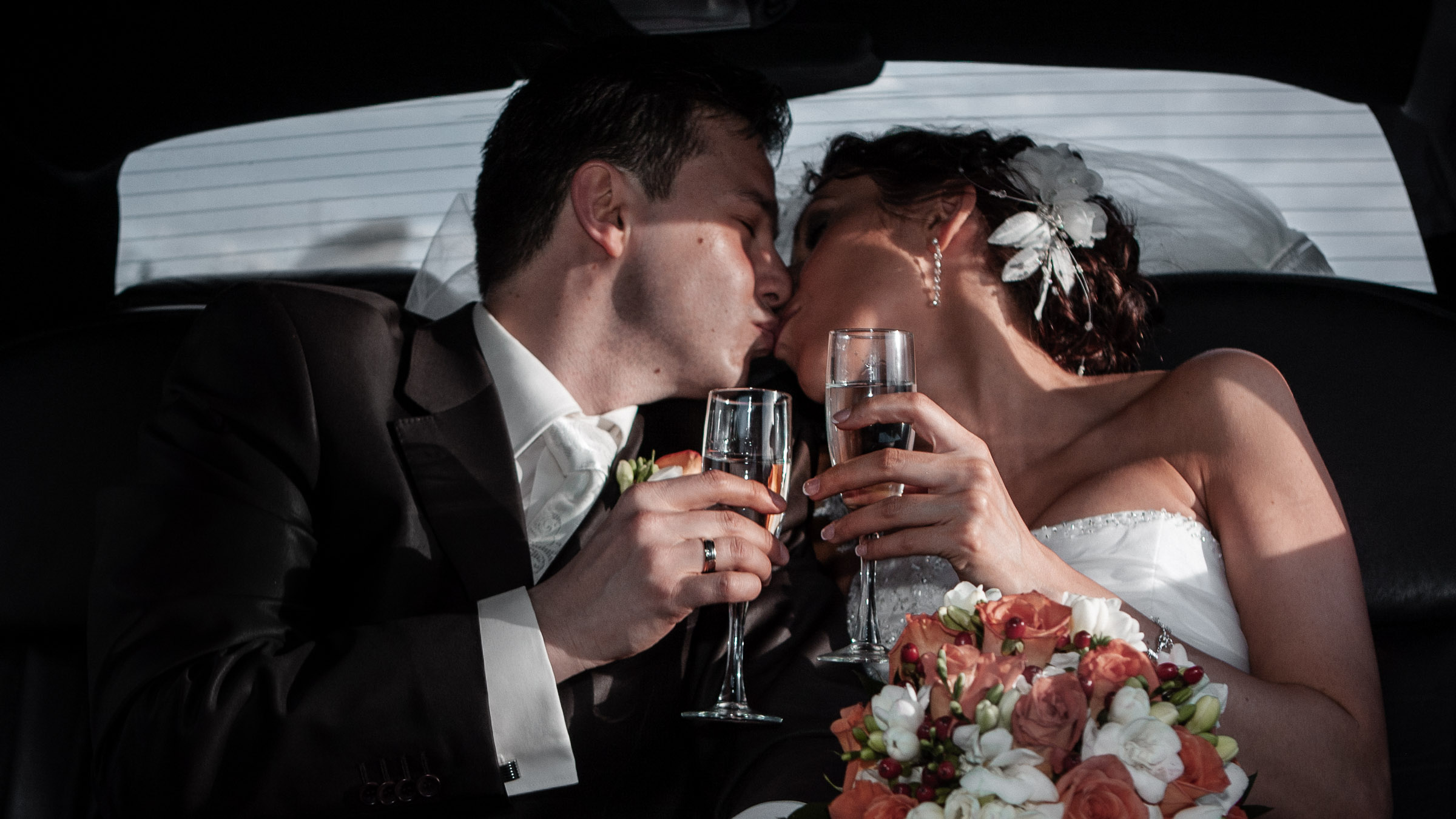 Bride and groom kissing in limo with champagne glasses after Las Vegas elopement captured in a cinematic editorial wedding photography style
