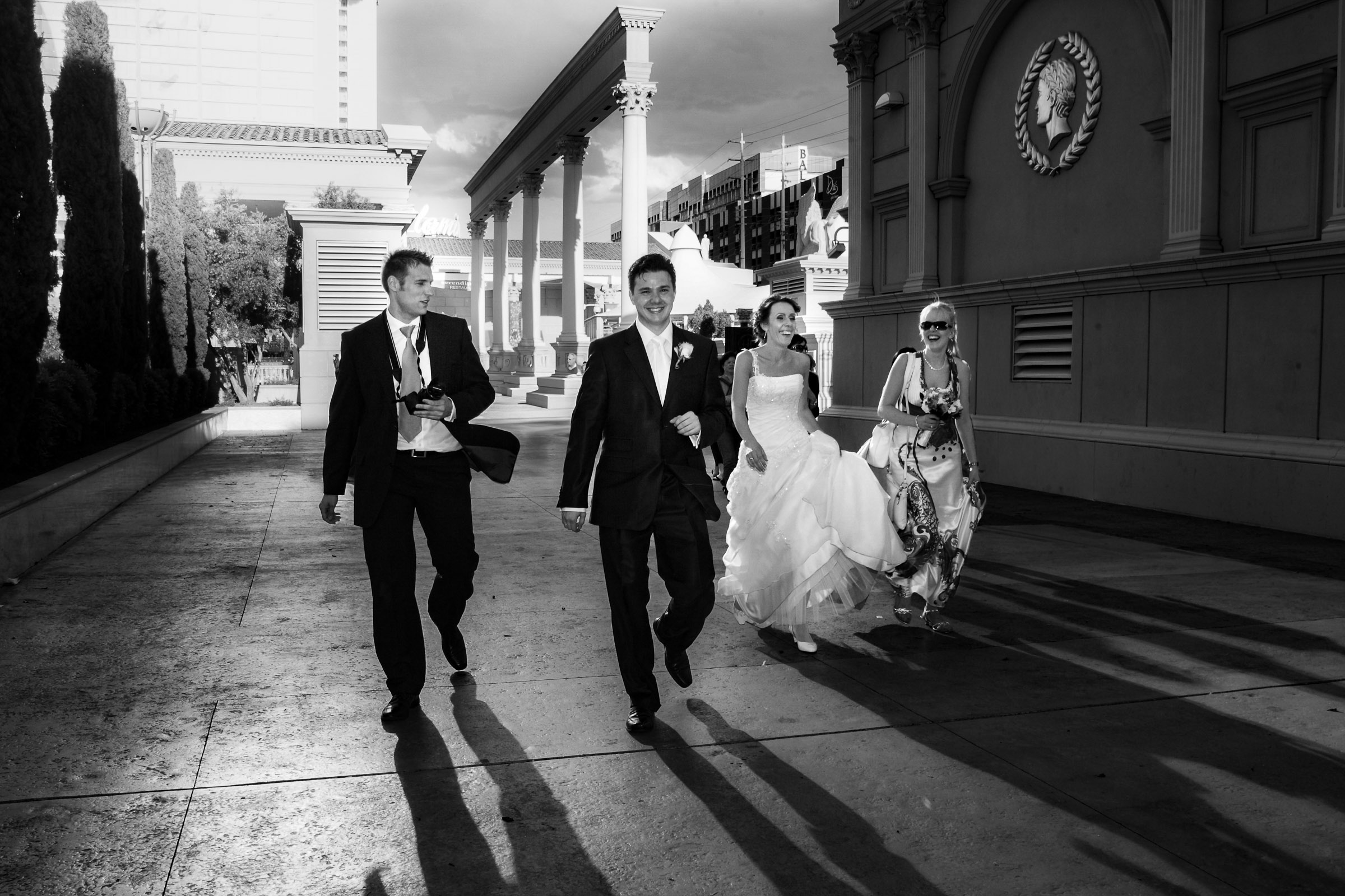 Bride and groom walking with wedding party at Caesars Palace Las Vegas captured in a cinematic editorial wedding photography style