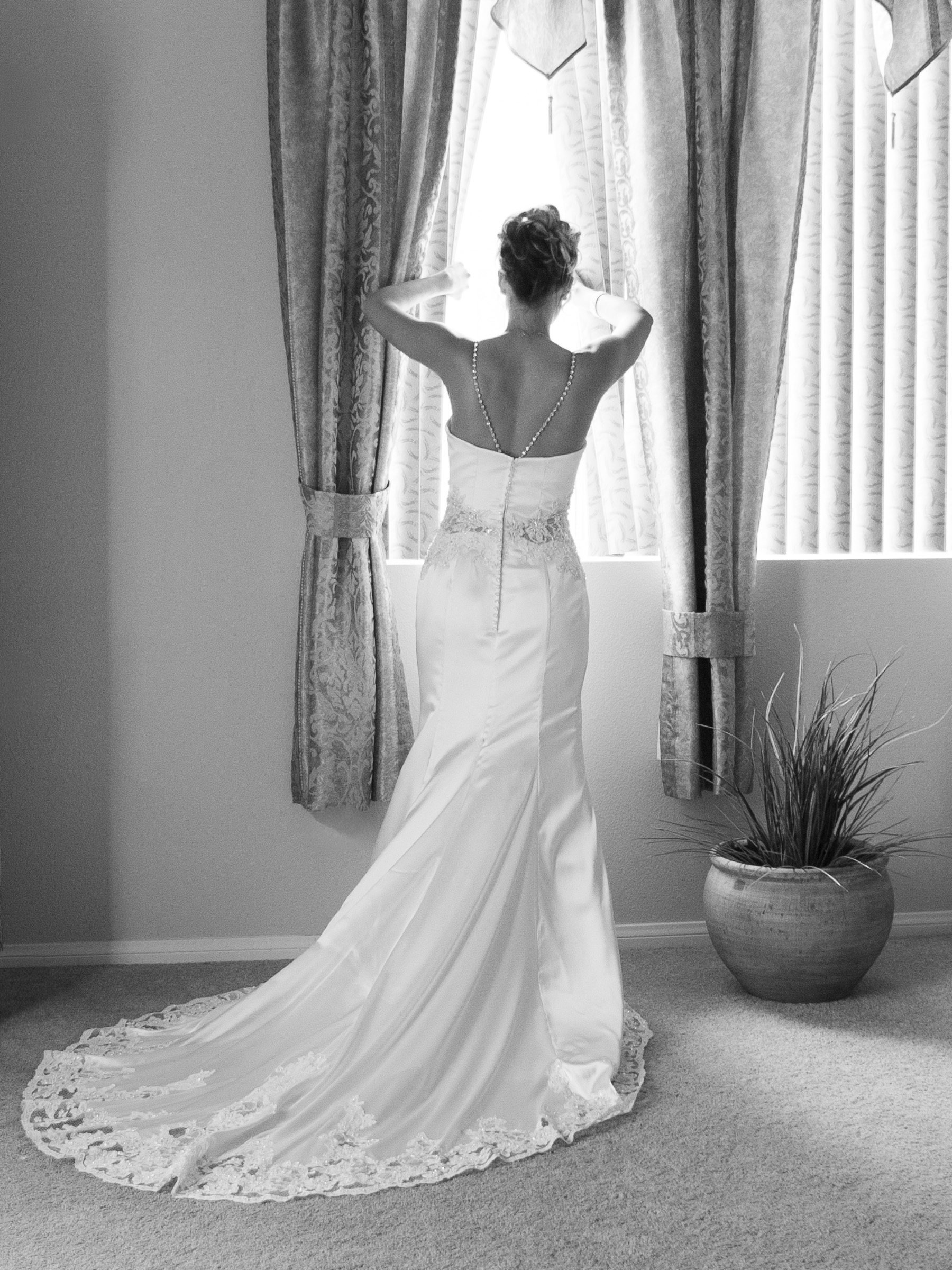Black and white getting ready image of bride looking out the window