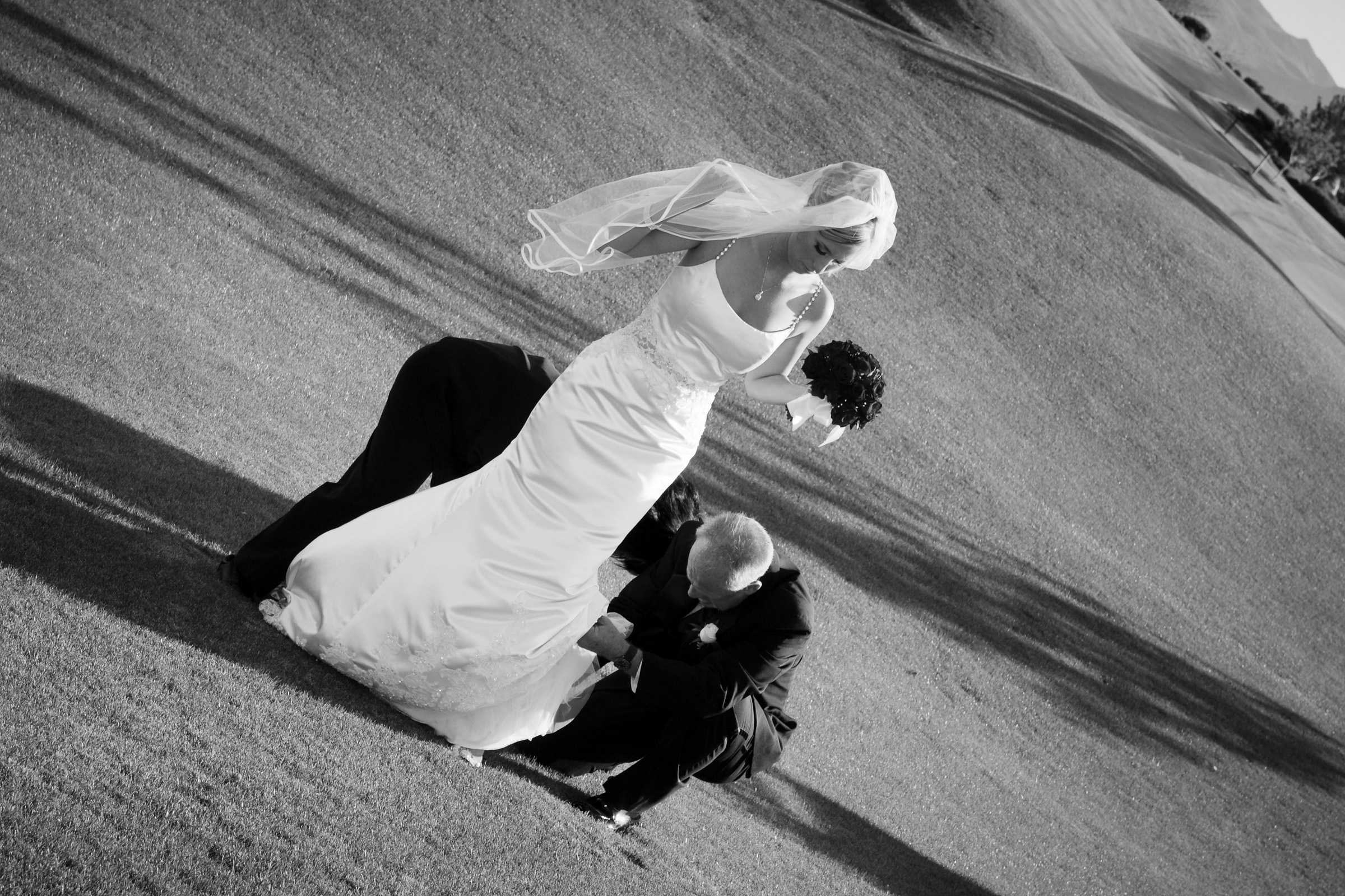 Wedding drama candid of brides heels getting stuck in the grass at a golf course wedding in black and white.